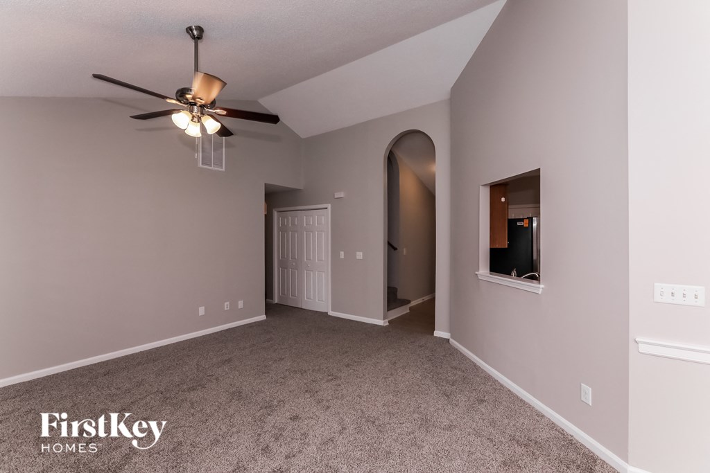 a living room with carpet and a ceiling fan