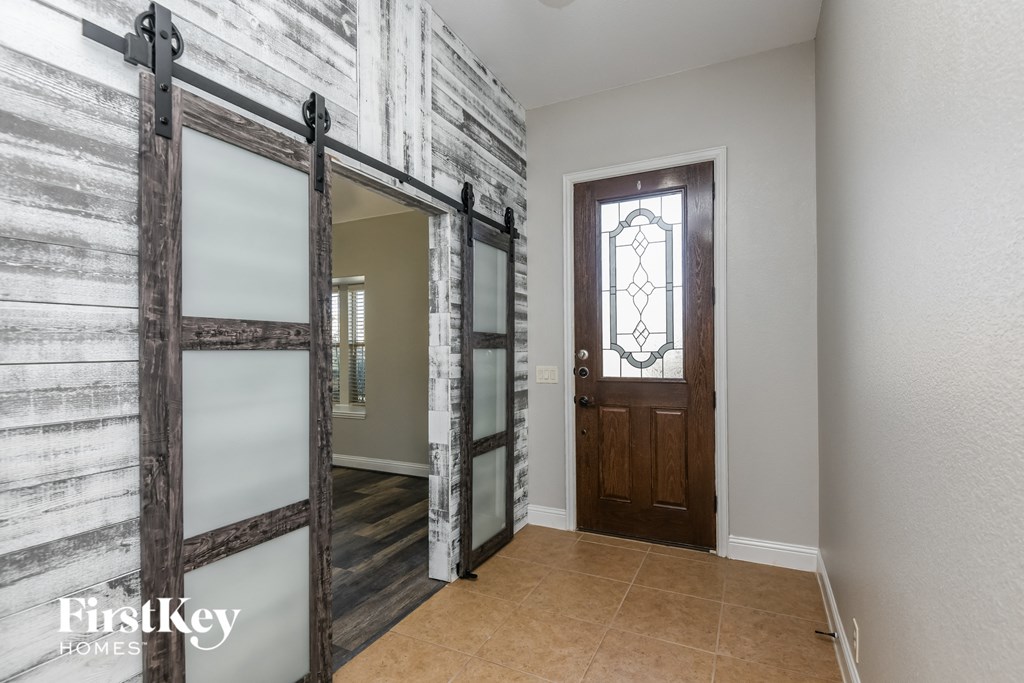 A wooden door with a glass panel is in a room with a white wall.