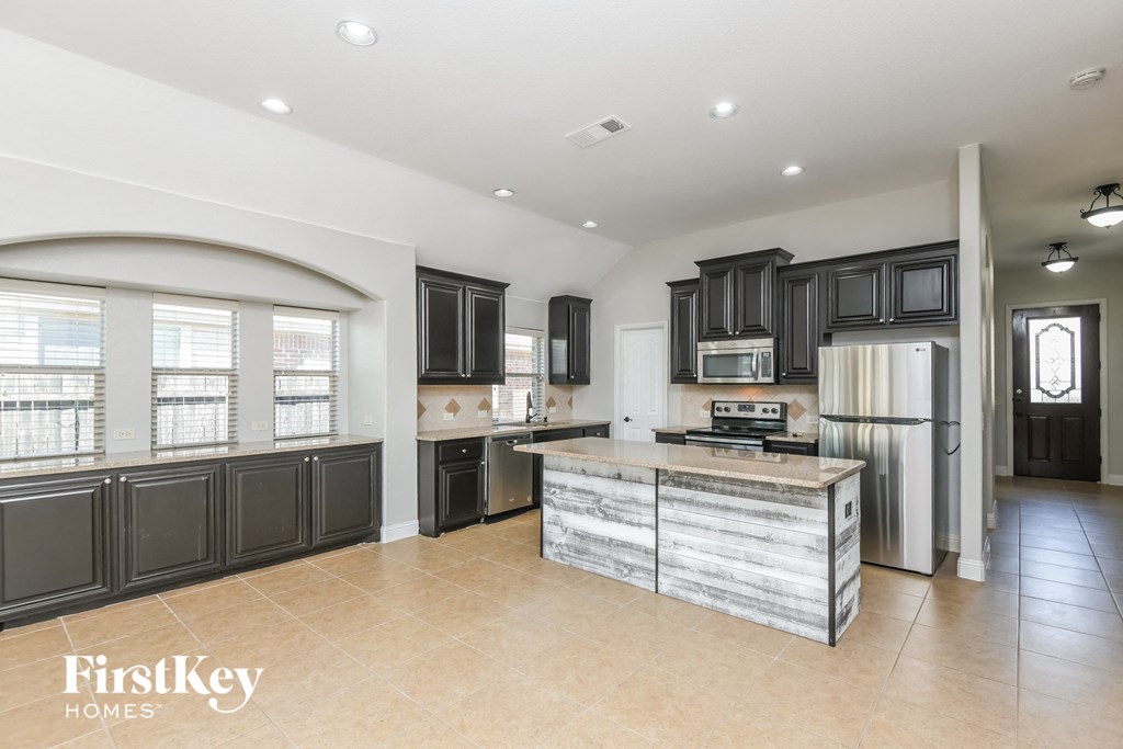A spacious kitchen with a wooden island and black cabinets.