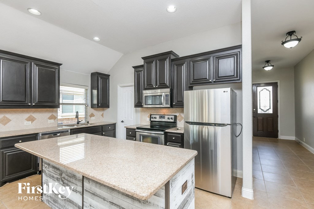 A kitchen with a refrigerator, oven, and microwave.