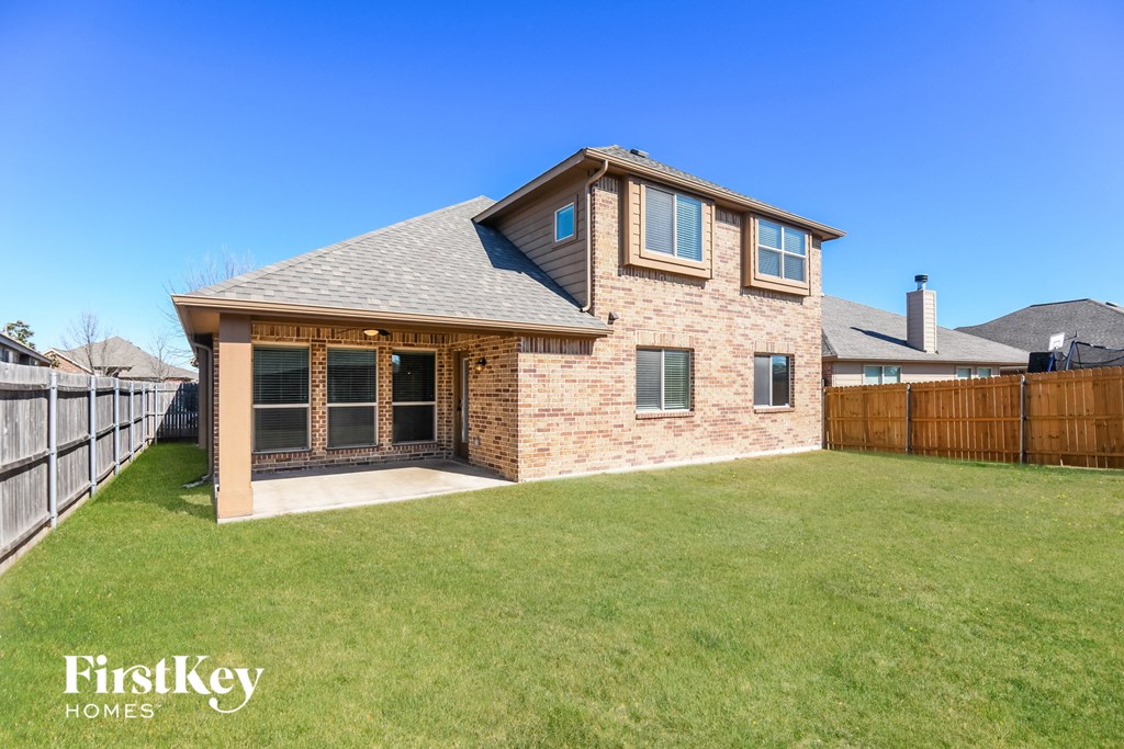 A house with a brown brick exterior and a grey roof is for sale.