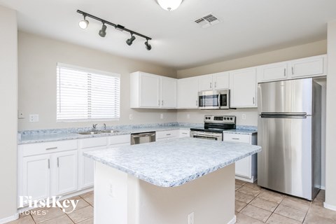 a white kitchen with stainless steel appliances and a marble counter top