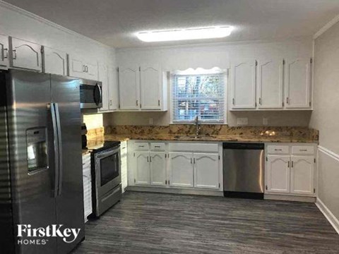 A kitchen with a refrigerator, microwave, oven, and cabinets.