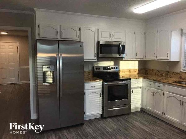 A kitchen with a stainless steel refrigerator, microwave, and oven.