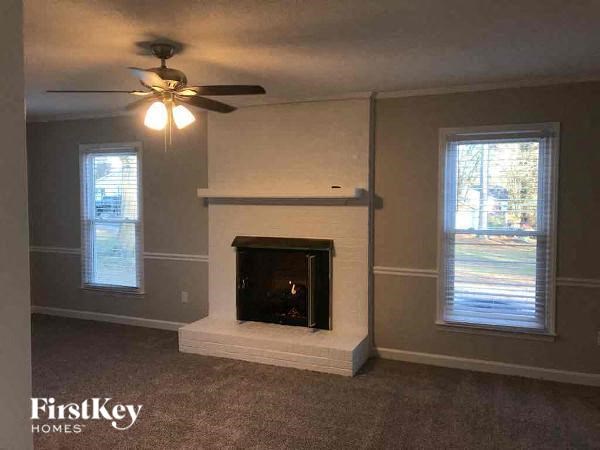 A living room with a fireplace and a ceiling fan.