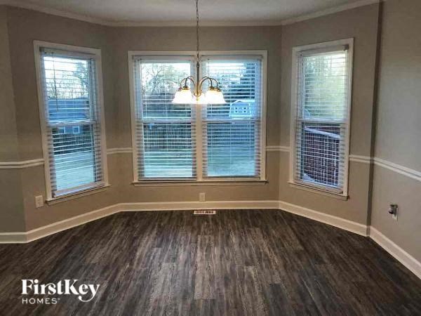 A room with wooden floors and three windows.