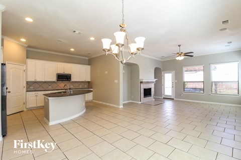 an open kitchen and living room with white cabinets and tiled flooring