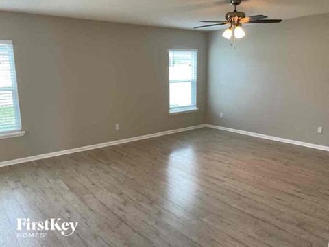 an empty living room with wood floors and a ceiling fan