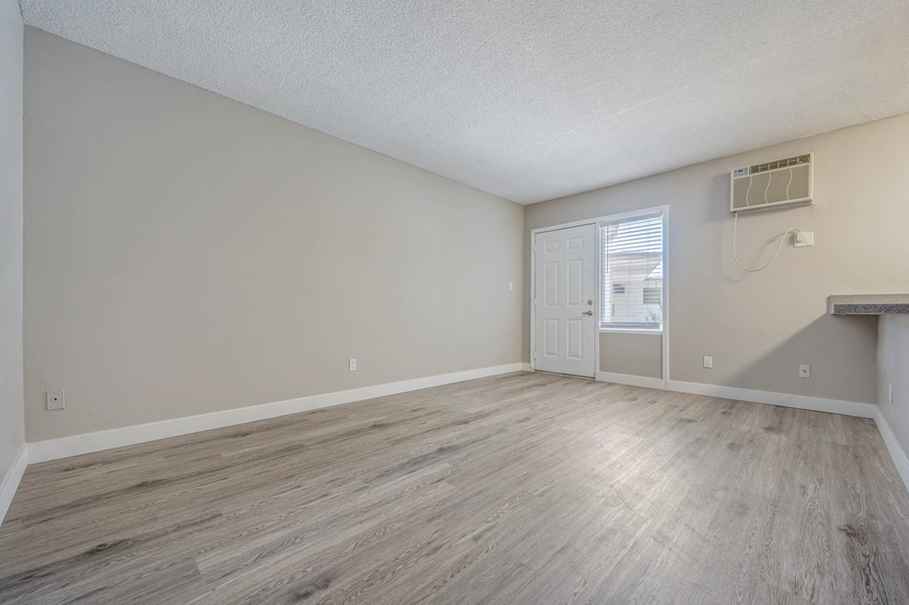 an empty living room with wood floors and a white door