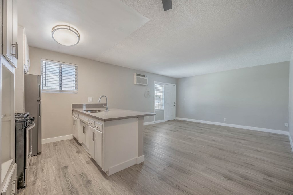 an empty kitchen and living room with a refrigerator and sink
