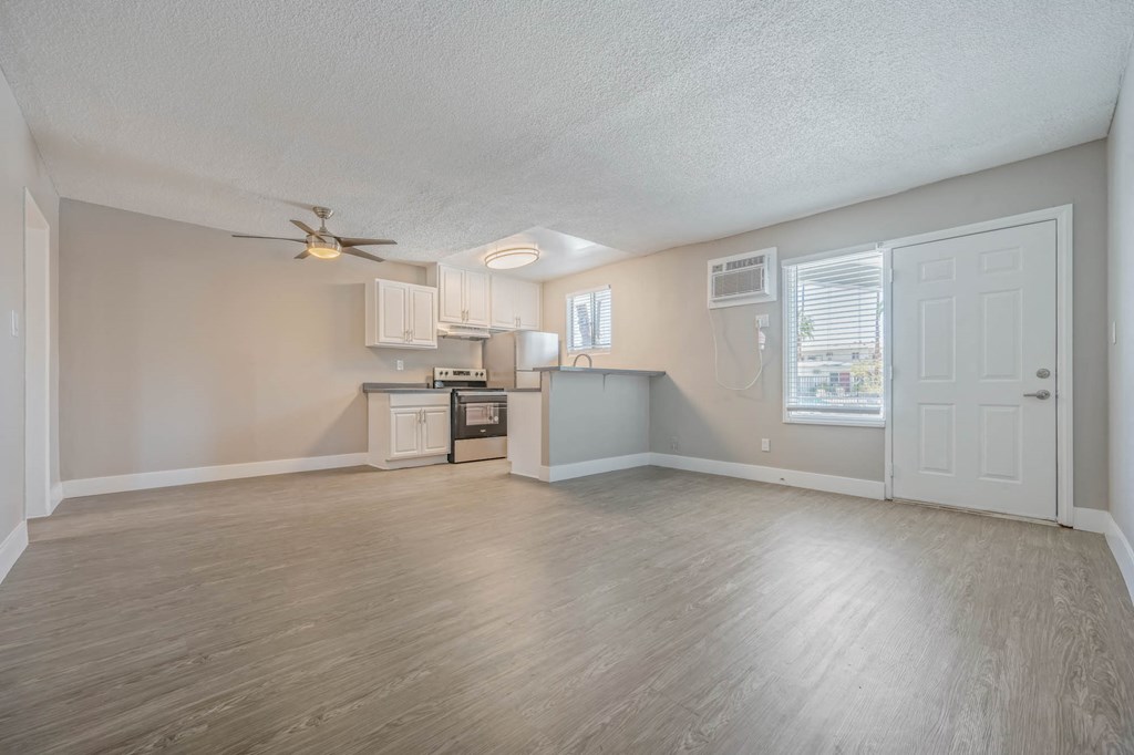 an empty living room and kitchen with a ceiling fan