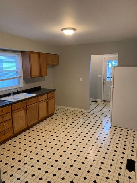 A kitchen with black and white tiles on the floor.