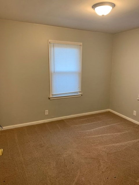 A room with a carpeted floor and a window.