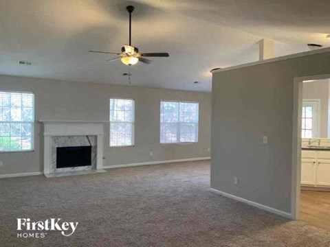 an empty living room with a ceiling fan and a fireplace