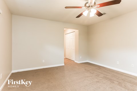 a spacious living room with carpet and a ceiling fan