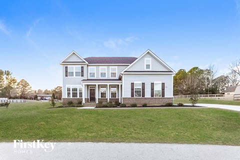 A white house with a brown roof and a sign that says "FirstKey Homes".