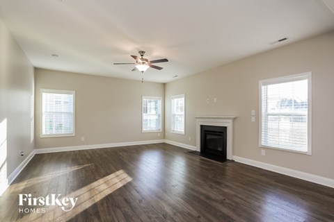 A spacious living room with wood flooring and a fireplace.