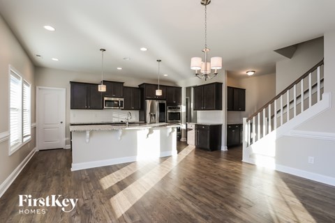 A spacious kitchen and living room with wooden floors and a staircase.