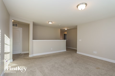A spacious empty room with a carpeted floor and white walls.