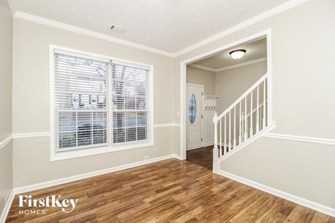 A room with wooden floors and a staircase leading to another room.