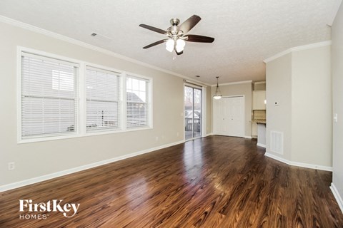 A spacious room with wooden floors and a ceiling fan.