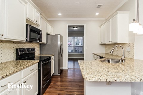 A kitchen with white cabinets and granite countertops.