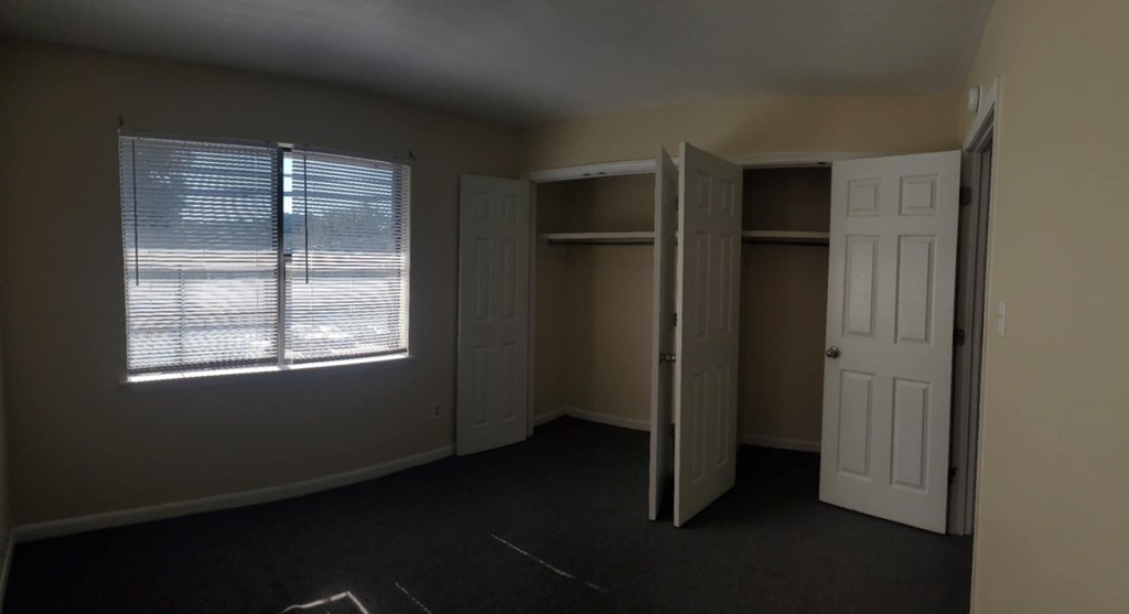 A room with a window, two closets, and a door.
