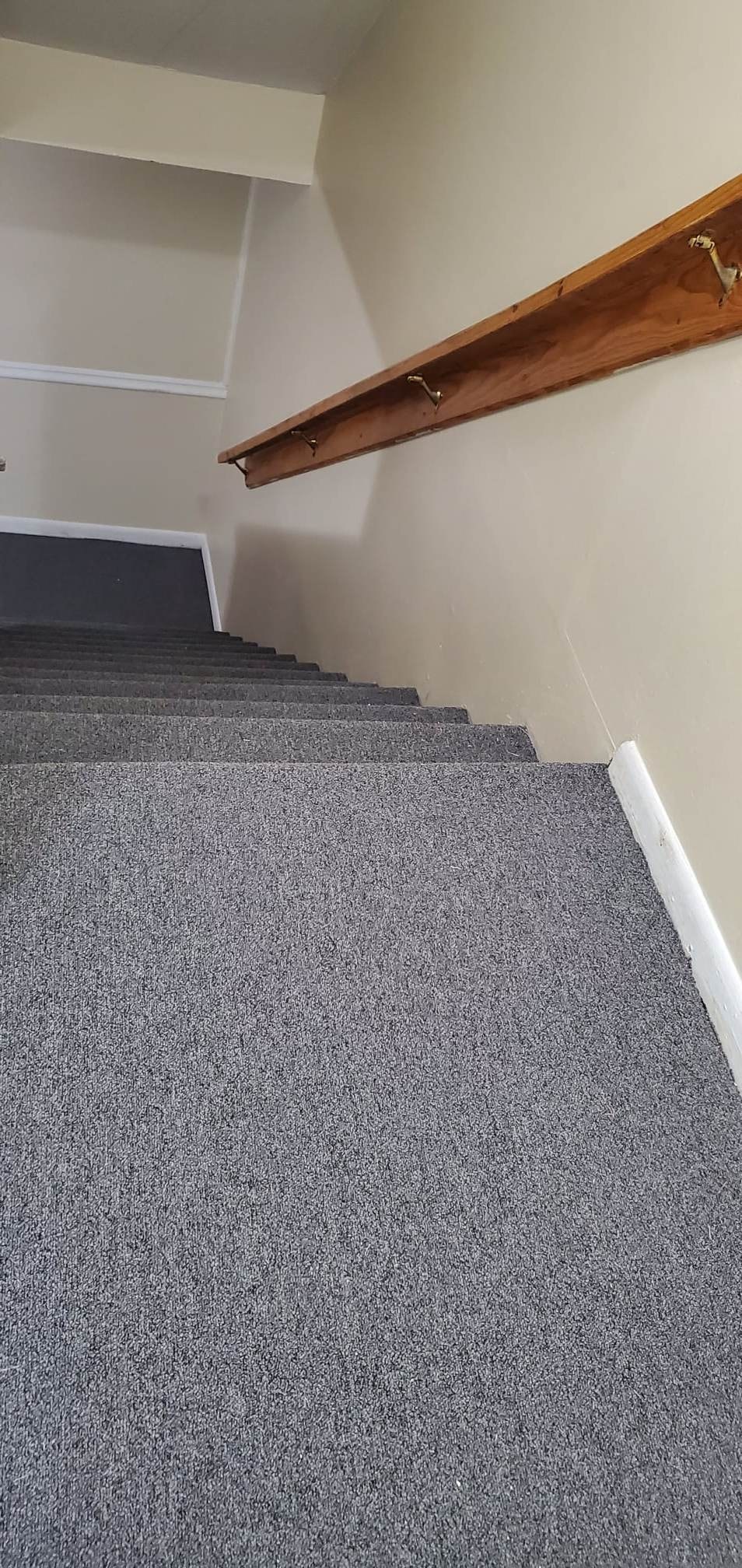 A staircase with a grey carpeted runner.