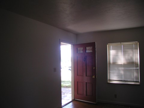 A red door is open to a hallway.