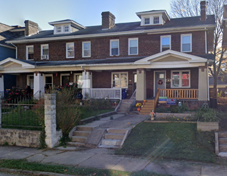 a large brick house with a porch and a sidewalk