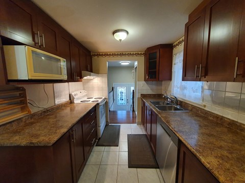 A kitchen with brown cabinets and a yellow microwave.