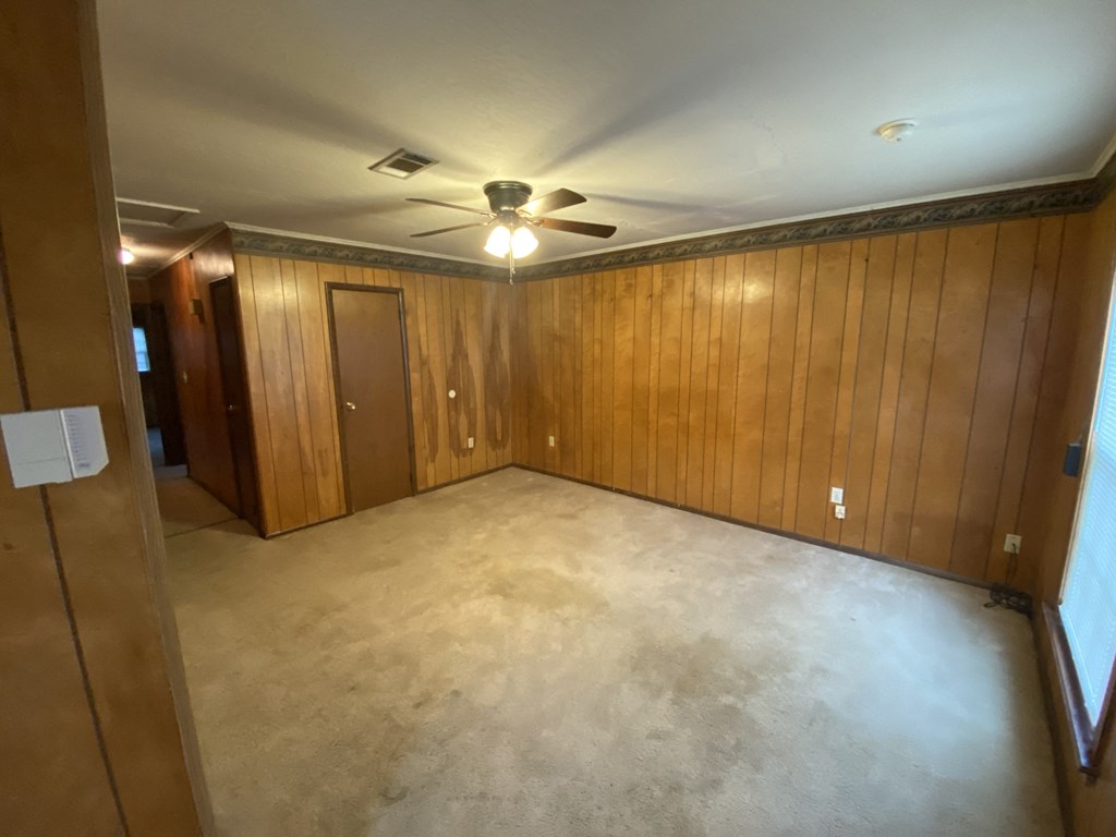 a living room with wood paneling and a ceiling fan