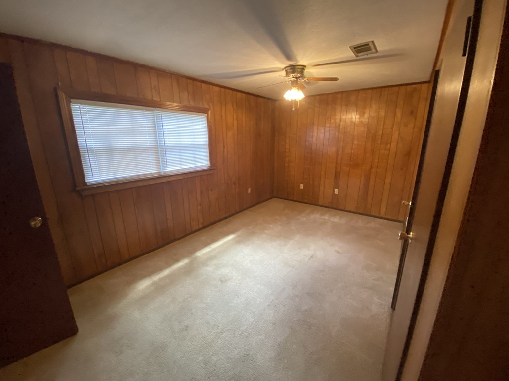 an empty room with a ceiling fan and a window