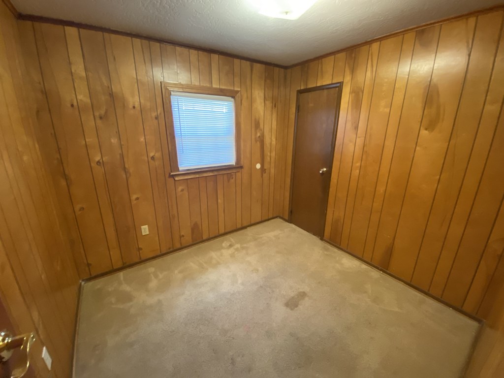 a room with a carpeted floor and a door and a window