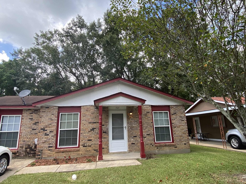 a small brick house with a yard and a tree
