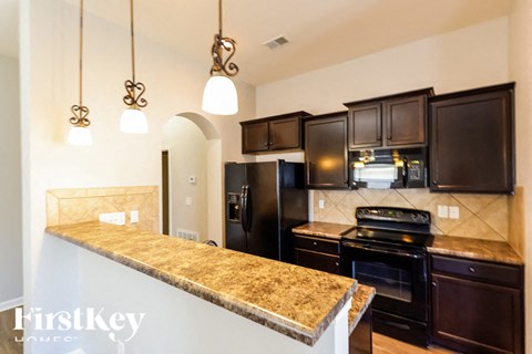 A kitchen with granite countertops and dark brown cabinets.
