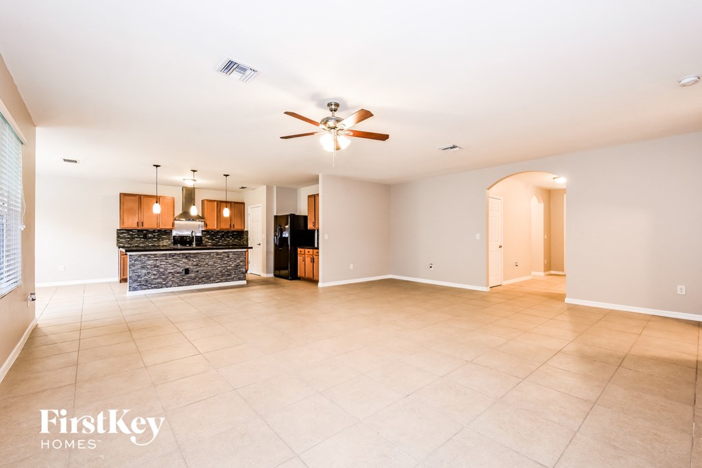 an empty living room and kitchen with a ceiling fan