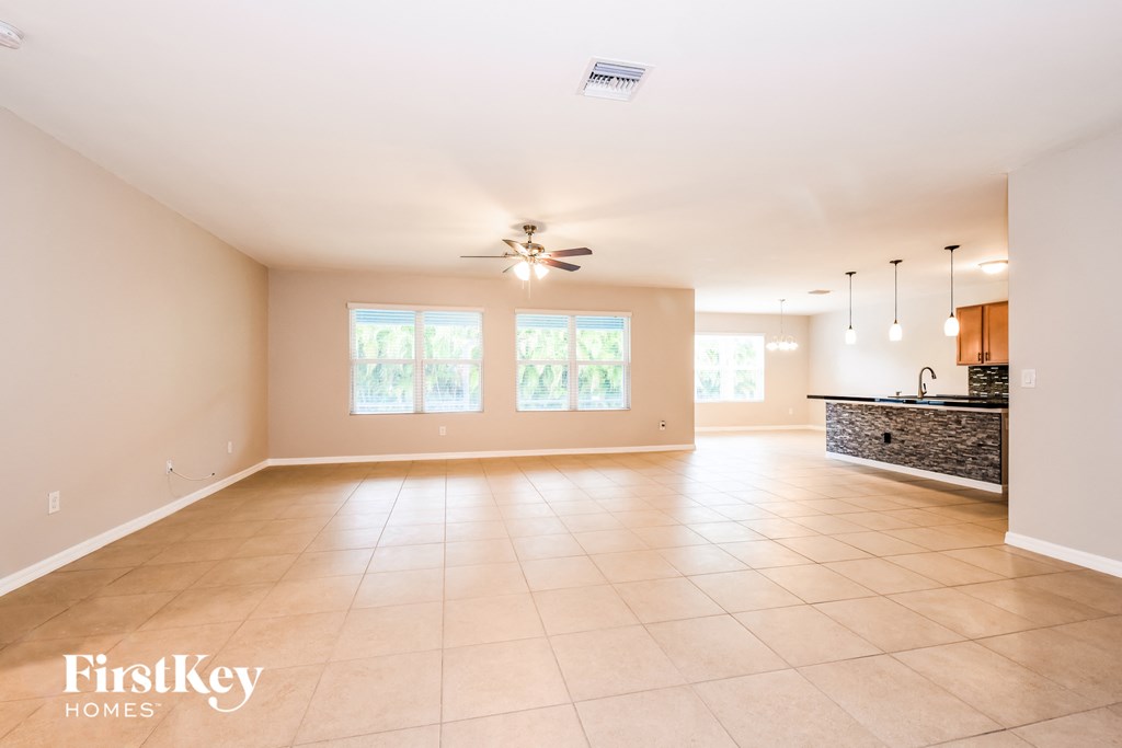 an empty living room and kitchen with a ceiling fan