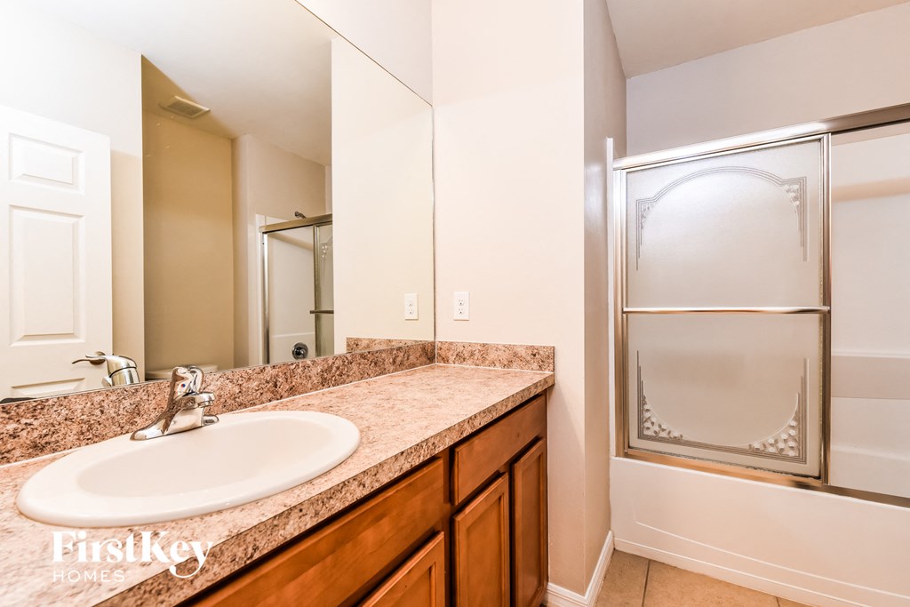 a bathroom with a sink and a shower and a mirror