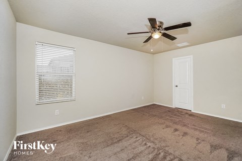 the spacious living room with carpet and a ceiling fan