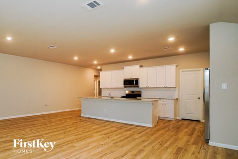 A kitchen with white cabinets and a wooden floor.