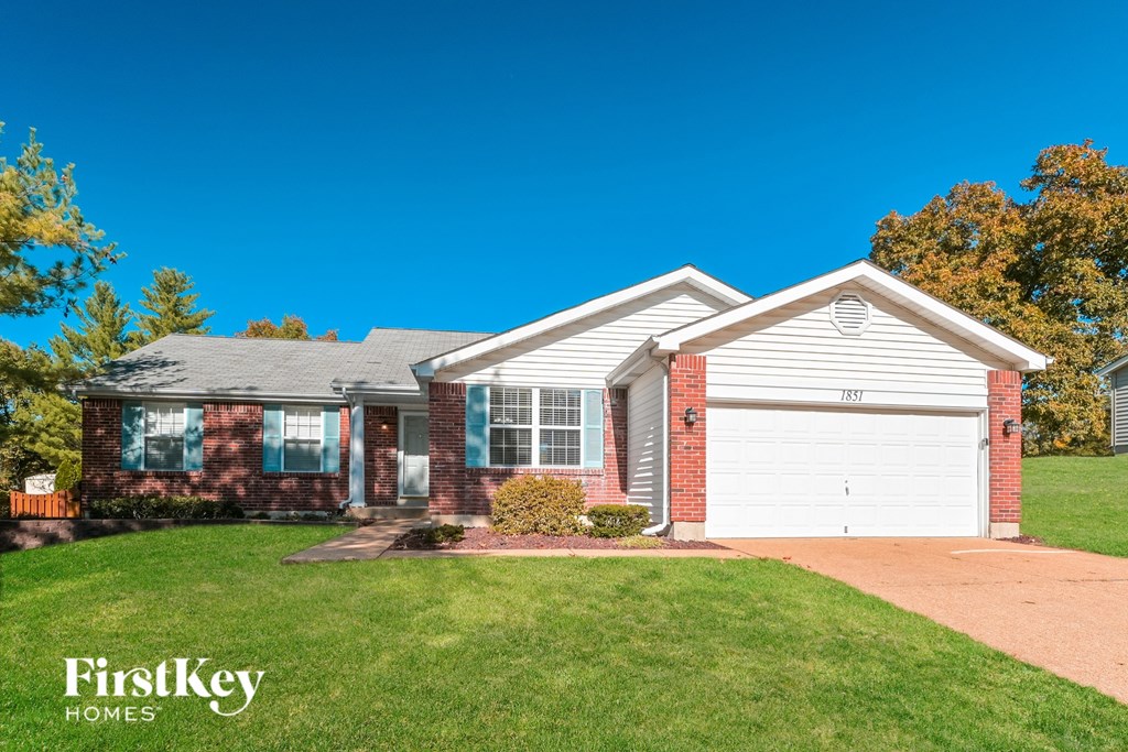 A house with a garage and a driveway in front of it.