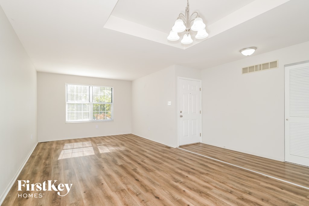 A room with wooden flooring and a chandelier hanging from the ceiling.