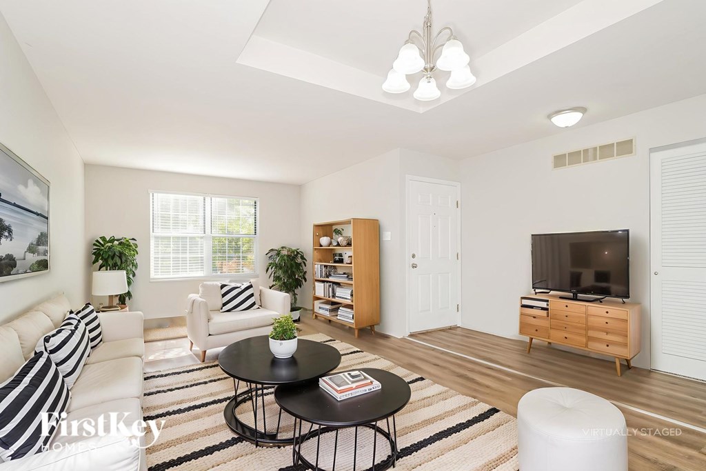 A living room with a black and white striped couch, a round table, and a television.