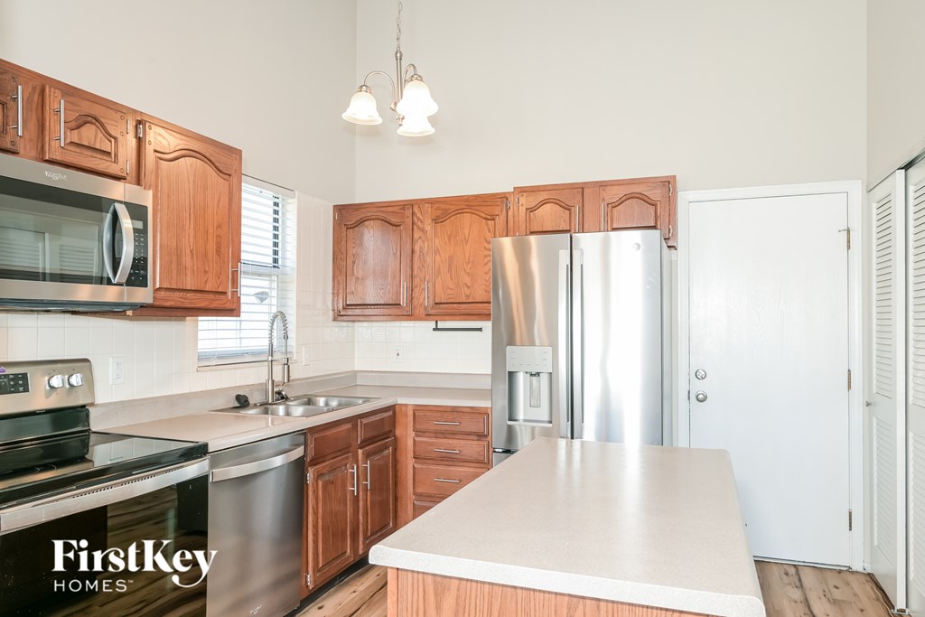 A kitchen with wooden cabinets and a stainless steel refrigerator.