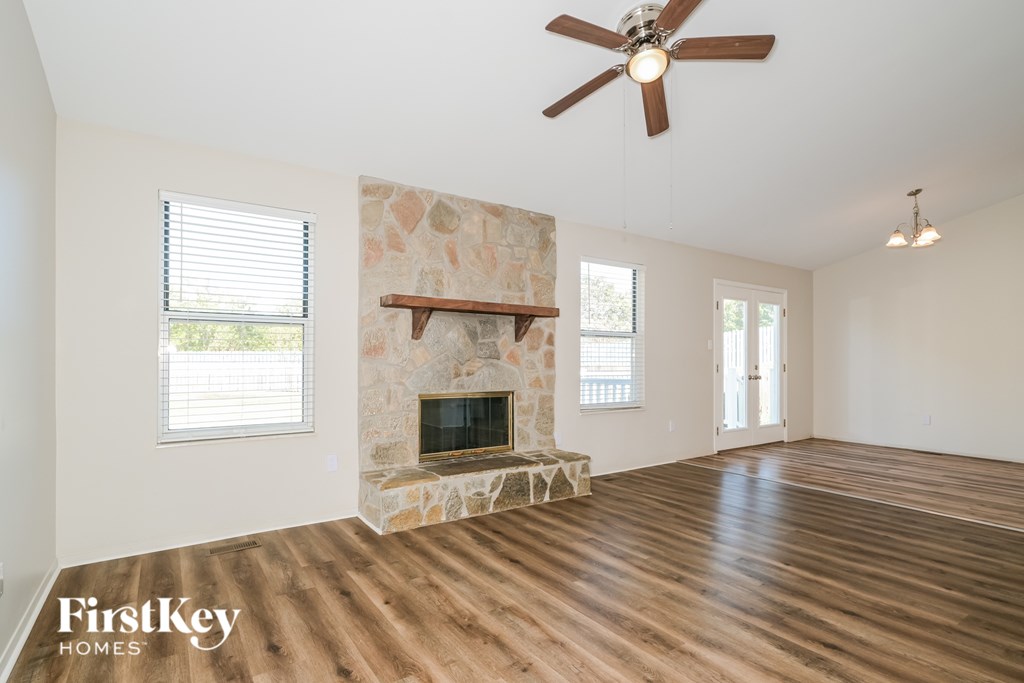 A spacious room with a stone fireplace and wooden flooring.