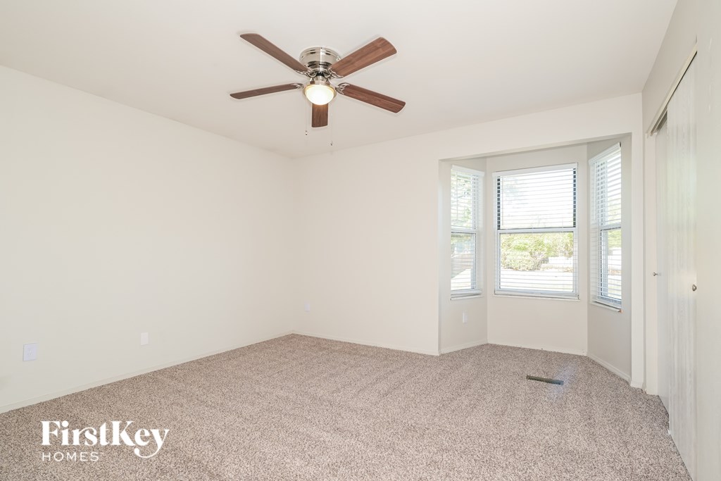 A room with a ceiling fan and a window with blinds.