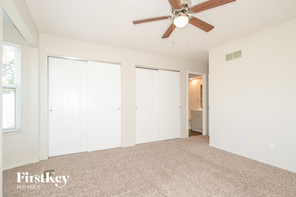A room with a ceiling fan and three white doors.