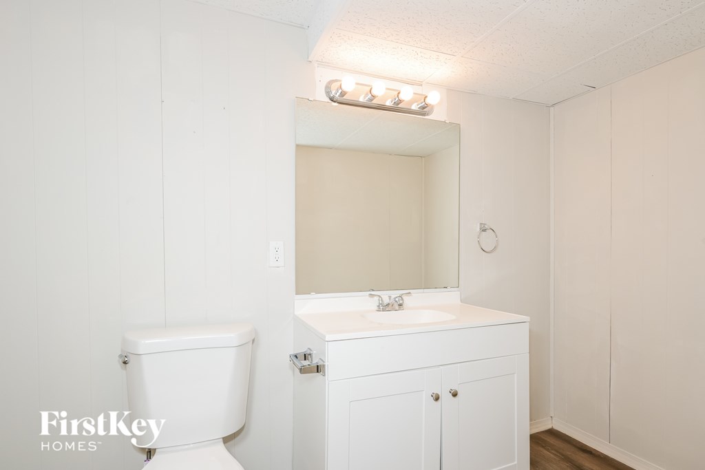 A white bathroom with a toilet, sink, and mirror.