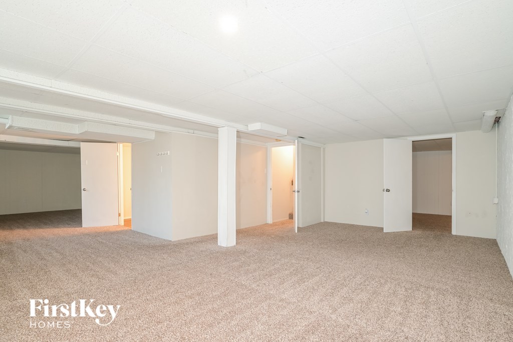A spacious empty room with a carpeted floor and white walls.